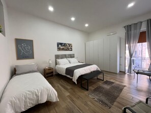 Een moderne slaapkamer met twee bedden, een bankje, een bureau en uitzicht door een raam.
