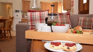 Ein gemütliches Wohnzimmer mit Essbereich, einer Kaffeemaschine und einem Teller Scones mit Marmelade.