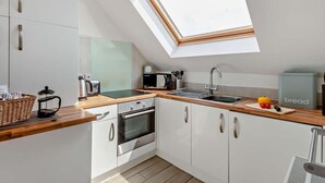 Een moderne keuken met dakraam, witte kasten en een houten aanrecht.
