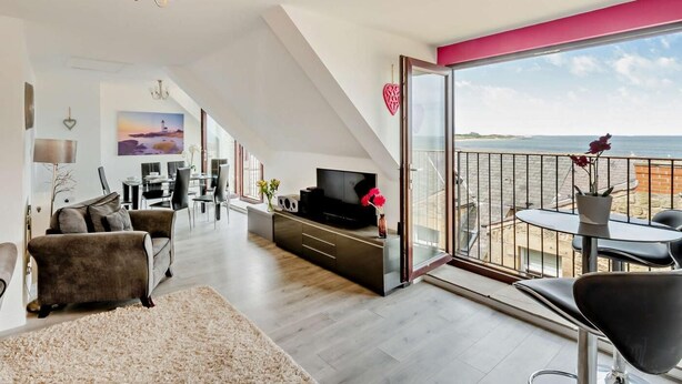 Een moderne woonkamer met een televisie, bank en eethoek.