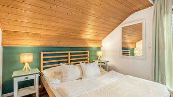 A bedroom with a wooden ceiling, a bed with white bedding, two bedside tables with lamps, and a mirror on the wall.