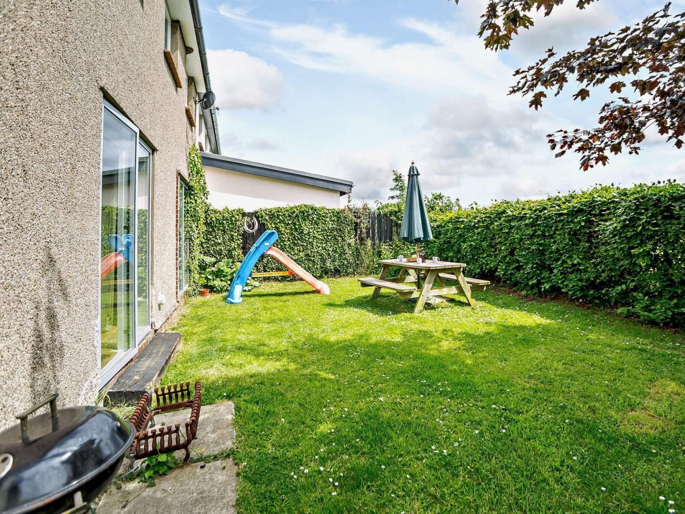 Un jardin avec un toboggan, une table de pique-nique et un barbecue.