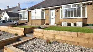 A residential house with a front garden, a driveway, and a parked car. - 3 Bed in Low Newton By The Sea (oc-cn203) (Newton-by-the-Sea)