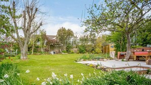 A well-maintained garden with a lawn, flowering plants, and a barbecue area. - 3 Bed in Low Newton By The Sea (oc-cn203) (Newton-by-the-Sea)
