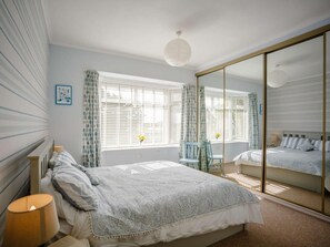 A bedroom with a bed, a mirror, a chair, and a window with curtains. - 3 Bed in Low Newton By The Sea (oc-cn203) (Newton-by-the-Sea)
