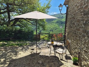 Eine Terrasse mit Tisch und Stühlen, einem hängenden Laternen und Blick auf ein üppiges Tal.