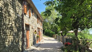A stone building with a gravel driveway and a garden with various plants. - Charming Tuscan apartment with a pool, views, and a private terrace (Toscana)