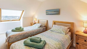 A bedroom with two beds, a skylight, a painting, and a bedside lamp. - 4 Bed in Beadnell (oc-cn167) (Beadnell)