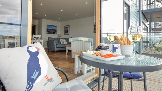 Ein gemütlicher Wohnbereich mit einer Couch, einem Esstisch mit Speisen und Getränken und einem Balkon mit Blick.