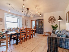 A dining area with a wooden table and chairs, a chandelier, and a cabinet with glass doors. - 4 Bed in Pitlochry (oc-59677) (Pitlochry)