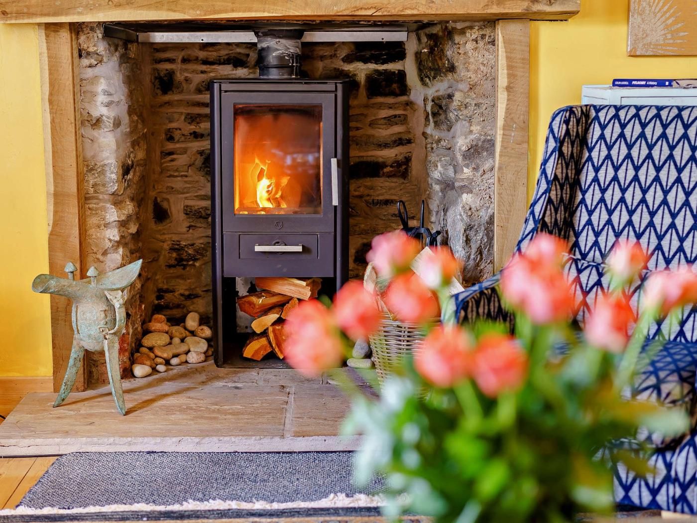 A wood-burning stove with logs, a stone fireplace, and a decorative metal sculpture.