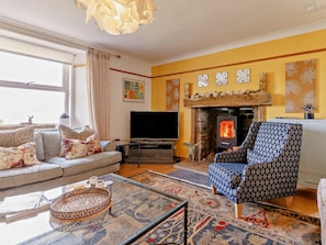 A living room with a sofa, armchair, TV, fireplace, and decorative wall art. - 4 Bed in Pitlochry (oc-59677) (Pitlochry)