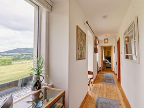 A corridor with a view of the outdoors, a vase with plants, and a framed picture on the wall. - 4 Bed in Pitlochry (oc-59677) (Pitlochry)