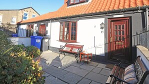 A traditional building with a red-tiled roof, a bench, and a blue trash bin. - 2 Bed in Seahouses (oc-cn220) (Seahouses)