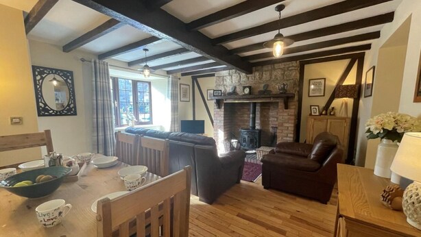 A cozy living room with a fireplace, wooden beams, and a dining area with chairs and a table. - 2 Bed in Seahouses (oc-cn220) (Seahouses)