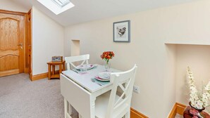 A dining area with a table set for two, a radio, and a framed picture on the wall. - 1 Bed in Alnwick (oc-cn215) (Alnwick)