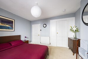 A bedroom with a bed, a dresser, a nightstand, a wall clock, and a radiator. - 2 Bed in Bideford (oc-59434) (Appledore)