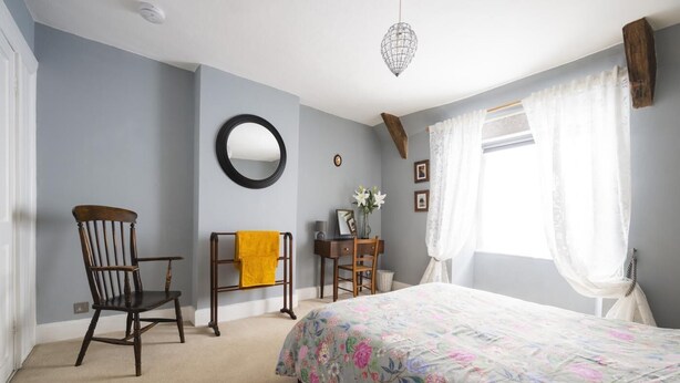 A bedroom with a bed, two chairs, a desk, a mirror, and a hanging light fixture. - 2 Bed in Bideford (oc-59434) (Appledore)