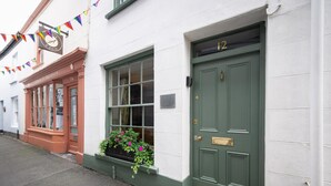 A building with a green door marked with the number 12, a window with a flower box, and a sign above the door. - 2 Bed in Bideford (oc-59434) (Appledore)