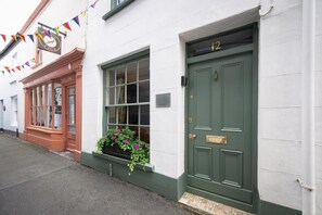 A building with a green door marked with the number 12, a window with a flower box, and a sign above the door. - 2 Bed in Bideford (oc-59434) (Appledore)