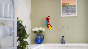 A room with a white archway, a parrot decoration, a painting of a coastal scene, a blue vase with flowers, and a patterned vase. - 2 Bed in Bideford (oc-59434) (Appledore)