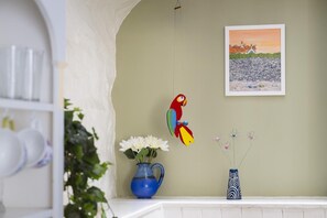 A room with a white archway, a parrot decoration, a painting of a coastal scene, a blue vase with flowers, and a patterned vase. - 2 Bed in Bideford (oc-59434) (Appledore)