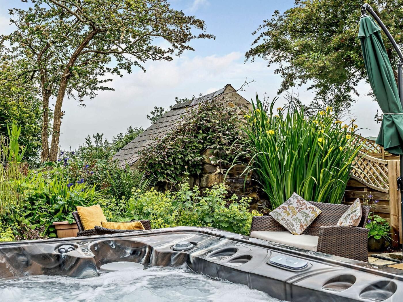 Ein Whirlpool mit Steinwand und Efeu im Hintergrund.