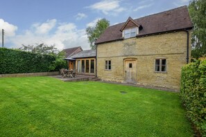 A stone house with a well-maintained lawn and a patio area. - 2 Bed in Ludlow (oc-59293) (Richards Castle)