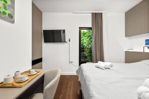A hotel room with a bed, a desk with a tray of breakfast items, a TV mounted on the wall, and a window with a view of greenery. - Pure Bliss Villa With Jacuzzi (Tisno)