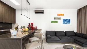 A modern kitchen with a bar area, a black sectional sofa, and artwork on the walls. - Pure Bliss Villa With Jacuzzi (Tisno)
