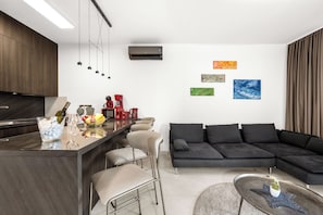 A modern kitchen with a bar area, a black sectional sofa, and artwork on the walls. - Pure Bliss Villa With Jacuzzi (Tisno)