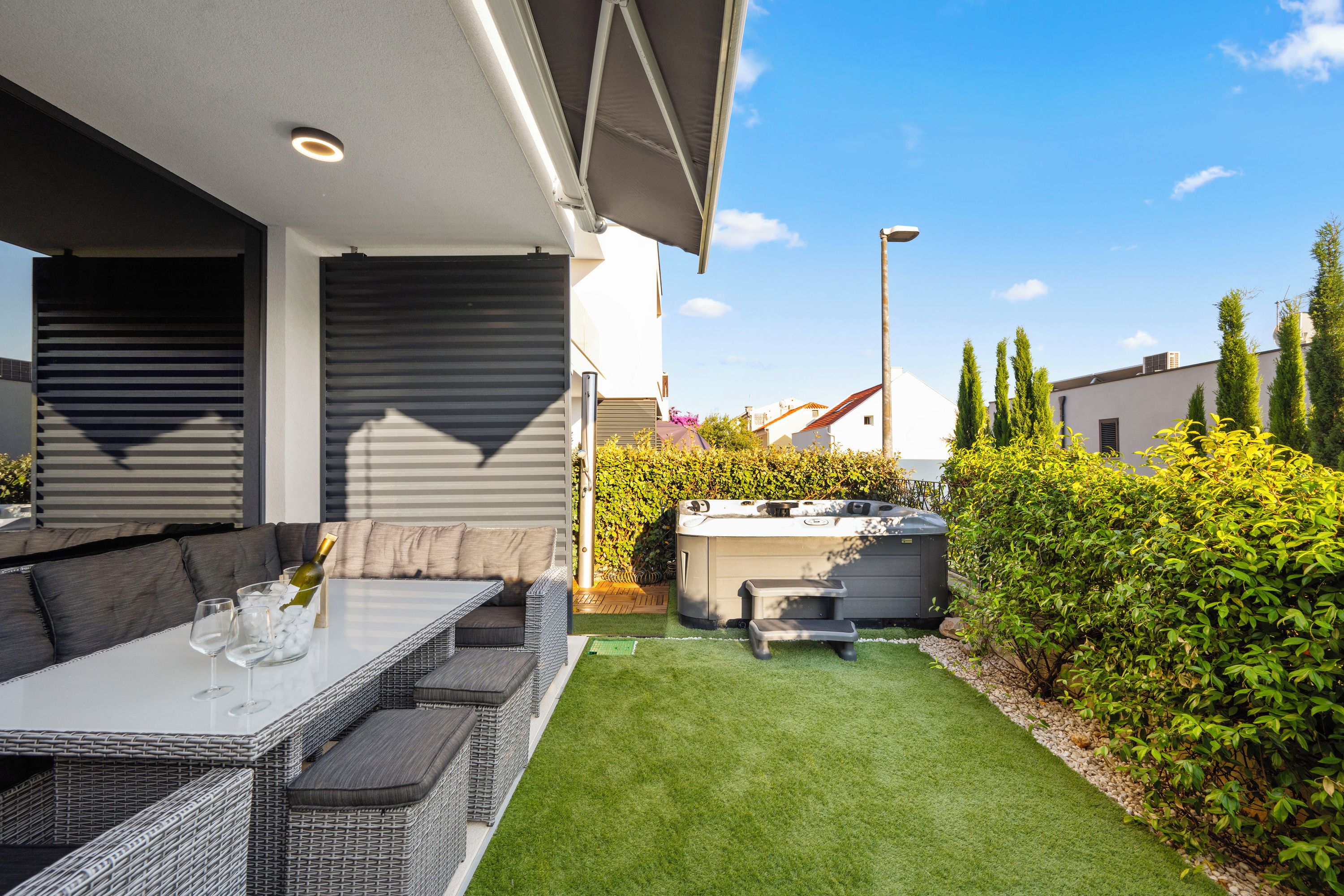 A patio with a table, cushions, and a hot tub.