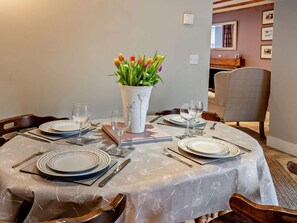 A dining table set with plates, cutlery, and glasses, a vase with flowers, and a chair. - 2 Bed in Swansea (oc-59663) (Ystradgynlais)