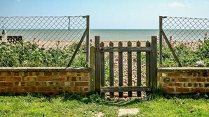 Ein Strandtor mit Backsteinmauer und Maschendrahtzaun.