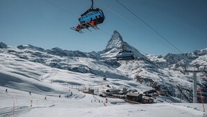 En skilift med skiløbere, et bjergtop og et sneklædt landskab.