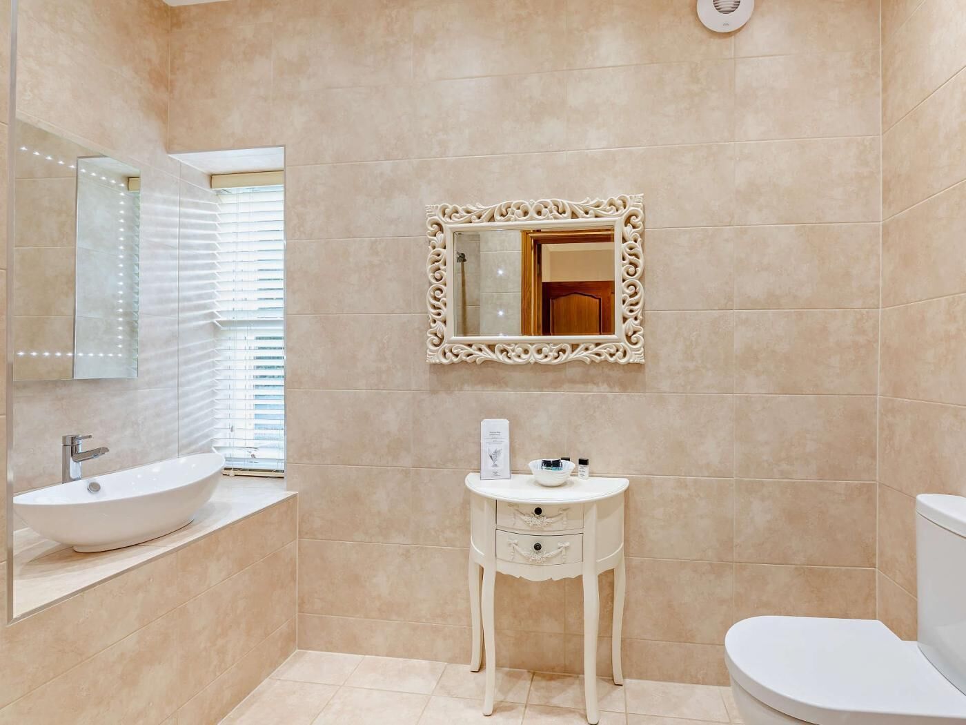 Een badkamer met een bad, een wastafel met spiegel, toilet en een opbergmeubel met lades.