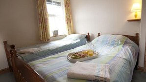 Ein Schlafzimmer mit zwei Einzelbetten, einem Nachttisch mit Lampe und einem Tablett mit Frühstücksgebäck.