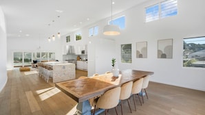 A spacious kitchen with a large island, modern pendant lighting, and large windows.