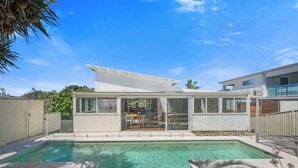 A modern house with a swimming pool, large windows, and a covered patio.