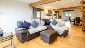 A modern living room with a sectional sofa, ottoman, and a dining area with a table and chairs. - 1 Bed in South Molton (oc-59339) (East Knowstone)