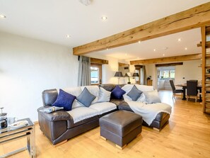 Ein modernes Wohnzimmer mit einer Eckcouch, einem Hocker und einem Essbereich mit Tisch und Stühlen.