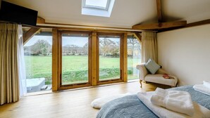 A bedroom with a large window, a bed, a sofa, and a skylight. - 1 Bed in South Molton (oc-59339) (East Knowstone)