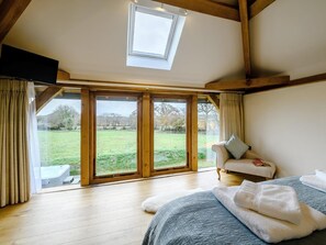 Ein Schlafzimmer mit großem Fenster, einem Bett, einer Schlafcouch und einem Oberlicht.