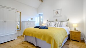 Een slaapkamer met een bed, nachtkastjes, een kledingkast en een raam met gordijnen.