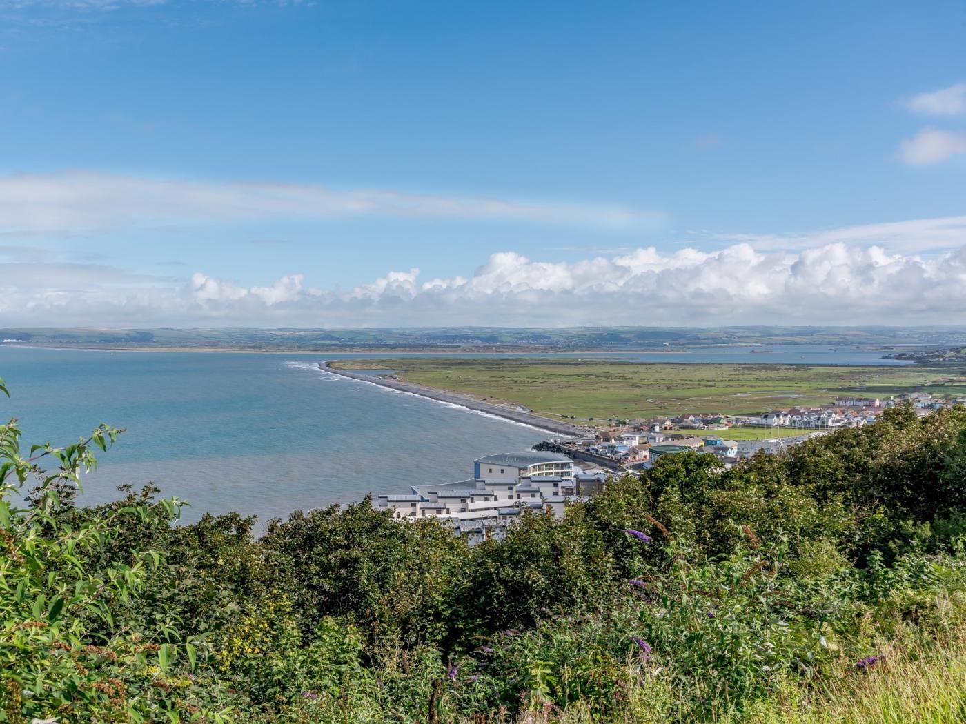 Une ville côtière offrant une vue sur la mer, une plage et un paysage vallonné.