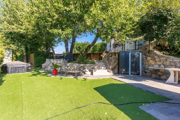 A well-maintained garden with a stone wall, a wooden bench, and a metal gate.