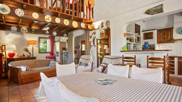 Una sala de estar acogedora con un sofá, una mesa de comedor con sillas y una zona de cocina con alacenas y un microondas.