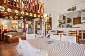 A cozy living room with a sofa, a dining table with chairs, and a kitchen area with cabinets and a microwave.
