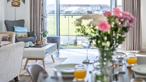 Ein modernes Wohnzimmer mit Essbereich, großen Fenstern und Blick ins Freie.