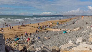 Ein Strand mit felsigem Gelände, einer Sandfläche und blauem Himmel.